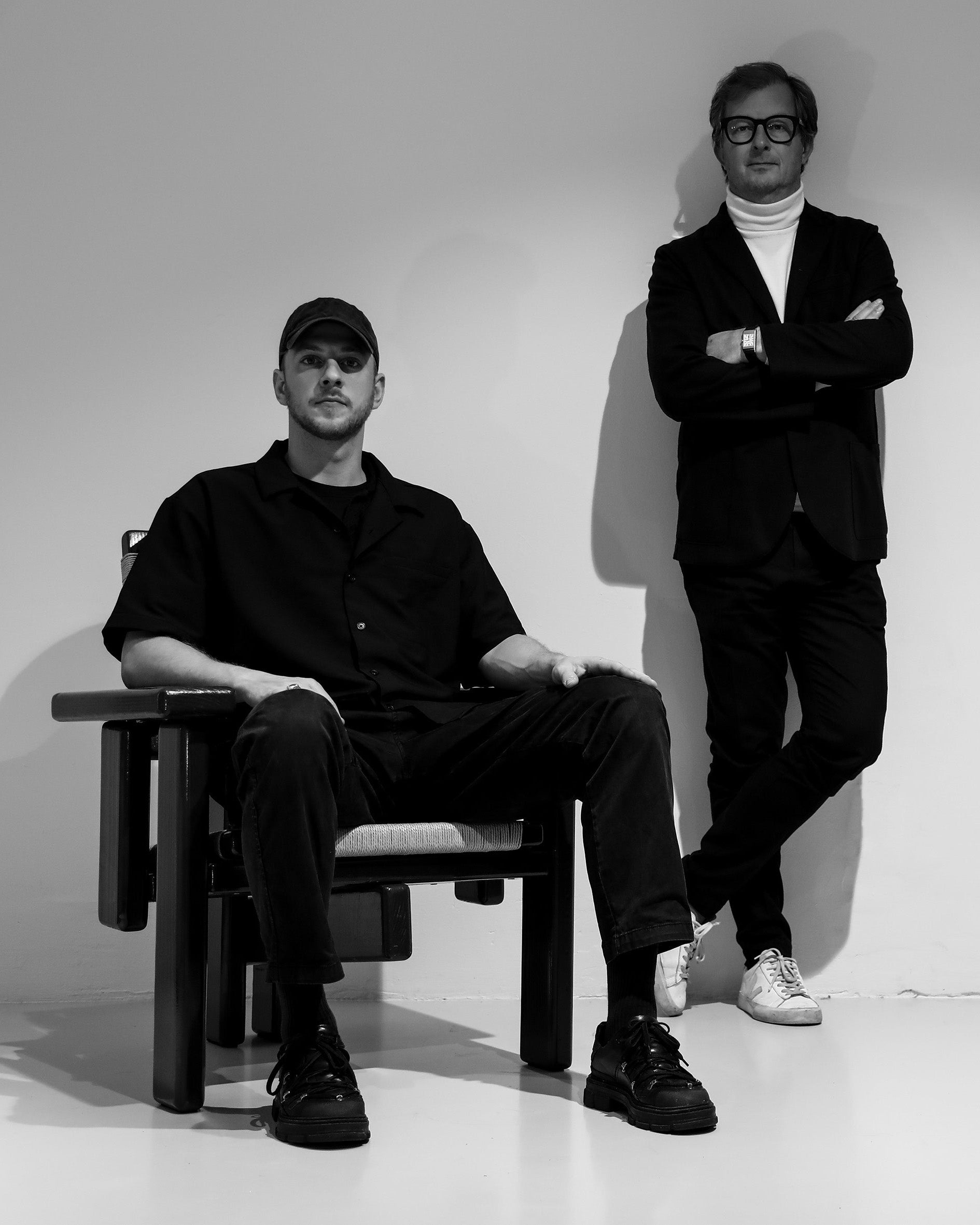 Wout and Lode, two men in black outfits posing against a plain background